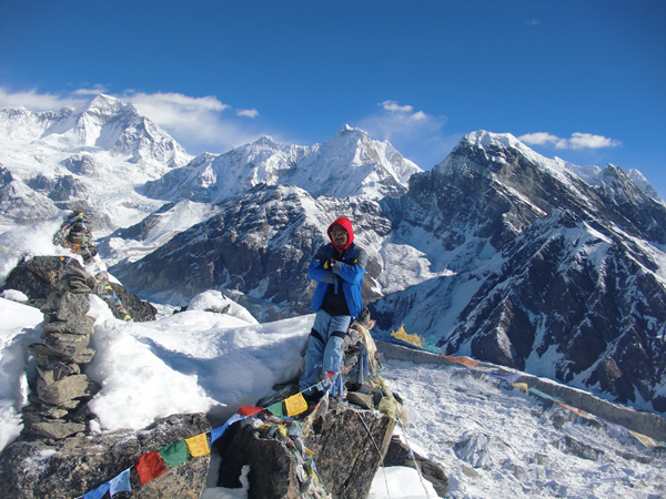 man standing on top of Kalapathhar mountain with Lobuche peak behind him